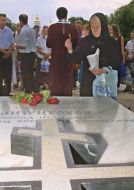A woman puts funeral candle on the grave