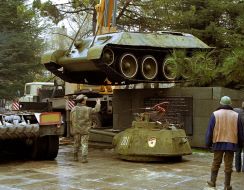 Рабочие автокраном снимают с постамента танк Т-34