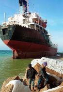Kids move across a rocky coast as the ”Yuzhny” tanker