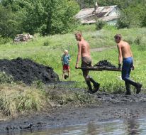 Youth extract coal from river floor