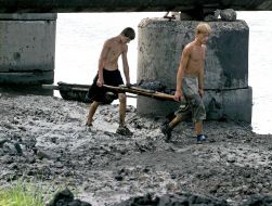Youth extract coal from river floor