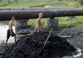 Youth extract coal from river floor