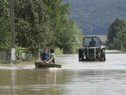 Люди плывут на лодке по затопленной улице
