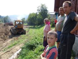 Місцеві мешканці спостерігають за роботою тракторів