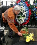 A man lays flowers on a grave