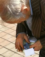 Пожилой мужчина рассматривает банковскую карточку