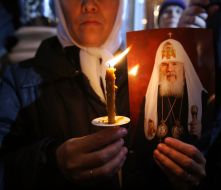 A woman holds the picture of Aleksiy II Patriarch Moscow and all Russia