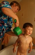 A mother washes son in bath