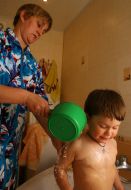 A mother washes son in bath