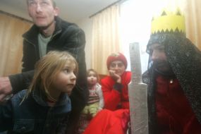 A girl looks at Christmas caroler in the fairy-tale hero suit