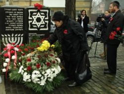 A woman lays flowers to the Holocaust victims monument