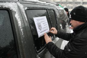 Водитель приклеивает к окну автомобиля плакат