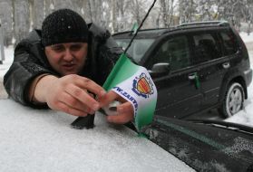 Водитель прикрепляет флажок к автомобилю