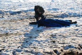 Мужчина осматривает тело погибшего