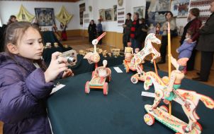 Девочка фотографирует деревянные игрушки