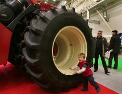 A boy stands near the tractor’s wheel