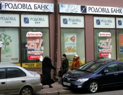 Passers-by pass near the “Rodovid Bank” department