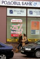 Passers-by pass near the “Rodovid Bank” department