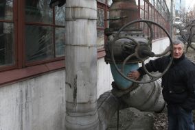 Worker near a valve on the pipe of boiler room