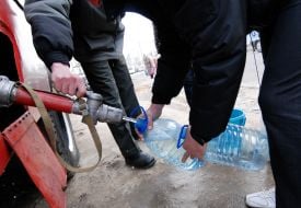 Сотрудник МЧС помогает мужчине набрать воду