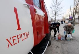 Сотрудник МЧС помогает пожилой женщине набрать воду