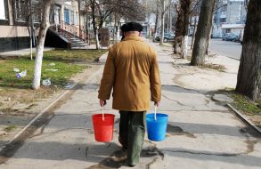 Мужчина несет ведра с водой