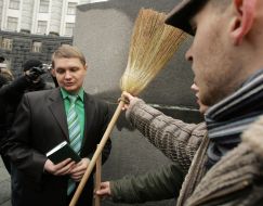 Protest action participants pass a broom