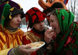 Участники празднования Масленицы кормят девушку блинами