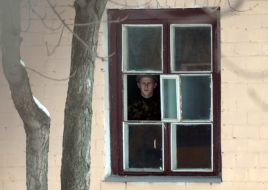A serviceman looks through window
