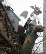 Рабочий устанавливает памятник Летающей корове