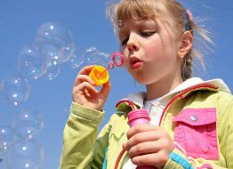 Девочка надувает мыльные пузыри