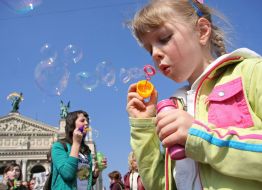 Девочка надувает мыльные пузыри