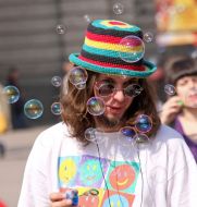 Молодой человек надувает мыльные пузыри