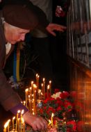 Жінка запалює свічку біля Меморіалу Героям Чорнобиля