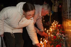 Жінка запалює свічку біля Меморіалу Героям Чорнобиля