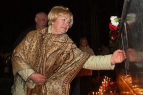 Жінка торкається рукою Меморіалу Героям Чорнобиля