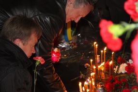 Чоловік ставить свічку біля Меморіалу Героям Чорнобиля