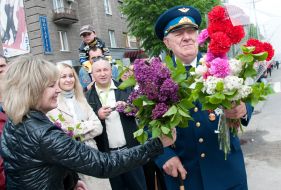 A woman give flowers to the Great Patriotic war veteran