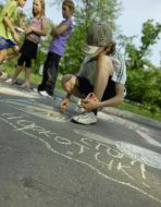 A boy draws by a chalk on asphalt