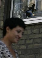 Женщина проходит возле разбитого окна