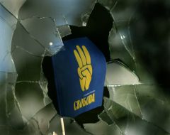 Флаг с эмблемой партии ”Свобода” в разбитом окне