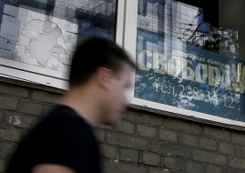 Мужчина проходит возле разбитого окна