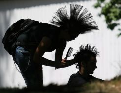 A girl-pank does a hair-do (mohawk) to the friend