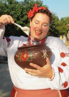 Женщина демонстрирует сметану в глиняном горшке