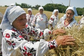 Пожилая женщина плетет снопы