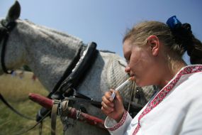 Девушка курит возле коня