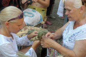 A woman teaches a girl to make a grass doll