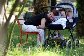 A grandmother sleeps on a perambulator with a grandchild