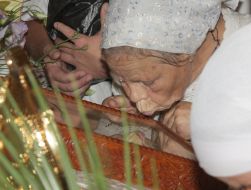 Пожилая женщина целует икону