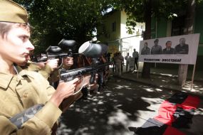 Участники акции протеста ”стреляют” по плакату